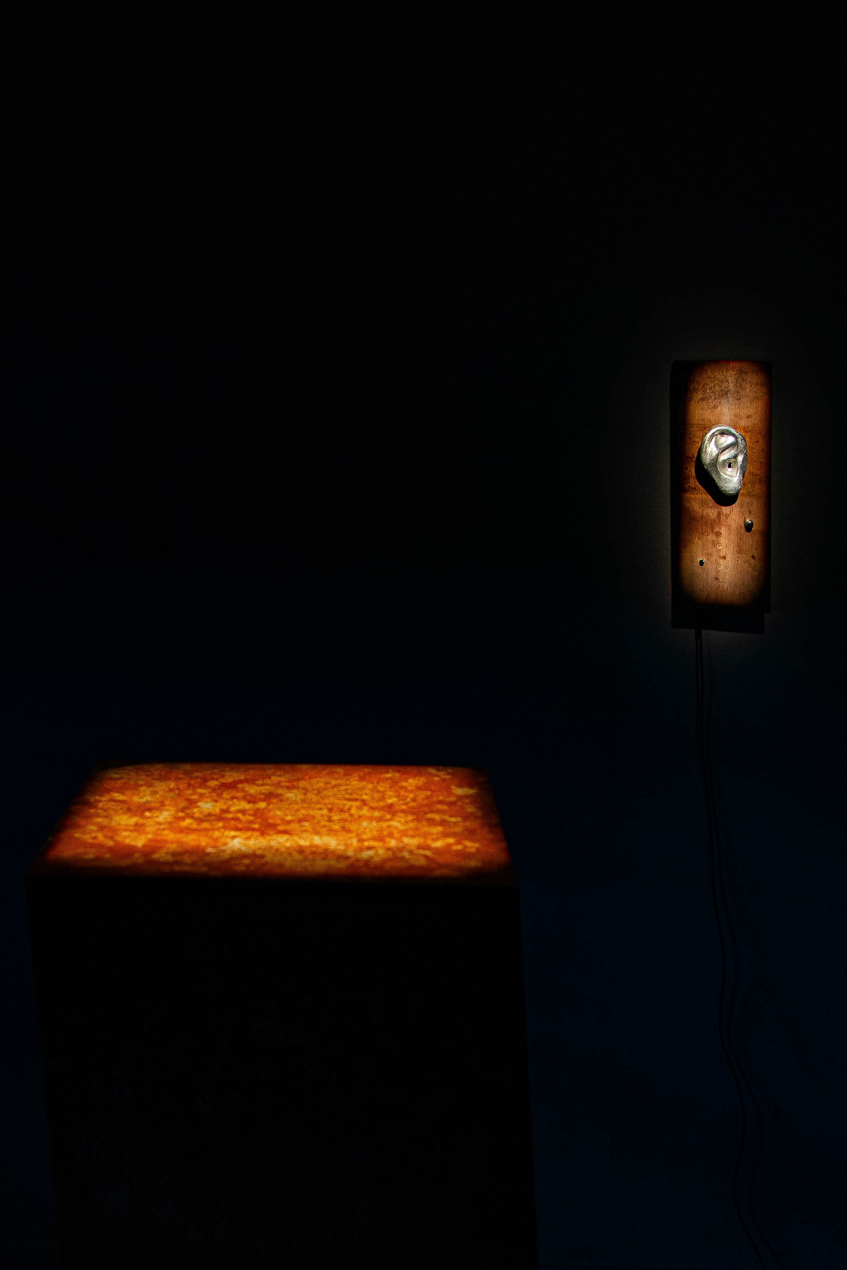 de ooho II — metal ear on found wood next to a steel cube.